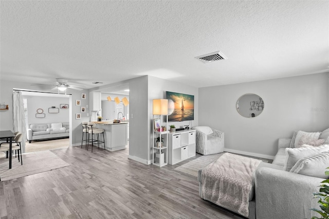 8004 Beaver Creek Loop, Hudson, FL 34667 - living room with a textured ceiling, light wood-style flooring, and a ceiling fan