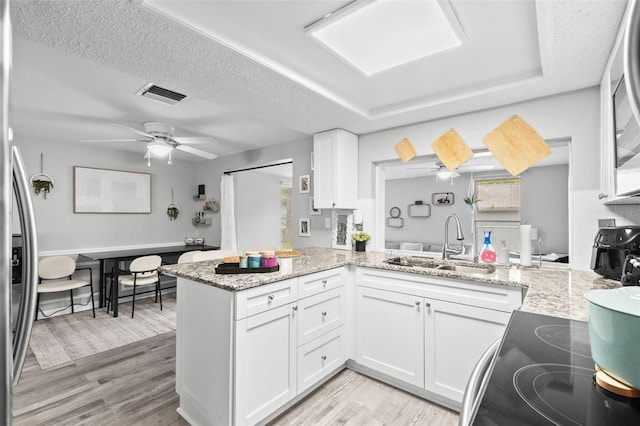 8004 Beaver Creek Loop, Hudson, FL 34667 - kitchen with a peninsula, white cabinetry, electric stove, light wood finished floors, and ceiling fan