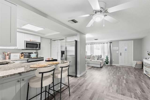 8004 Beaver Creek Loop, Hudson, FL 34667 - kitchen featuring appliances with stainless steel finishes, light stone counters, white cabinets, and a breakfast bar