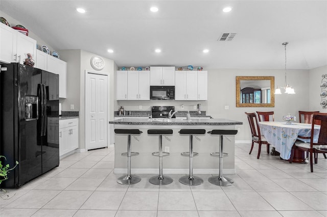 11303 Misty Moss Dr, Wimauma, FL 33598 - kitchen featuring black appliances, a breakfast bar, white cabinets, light tile patterned floors, and recessed lighting