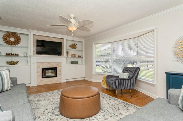 1304 63rd St NW, Bradenton, FL 34209 - living room with wood finished floors, a ceiling fan, crown molding, built in shelves, and a textured ceiling