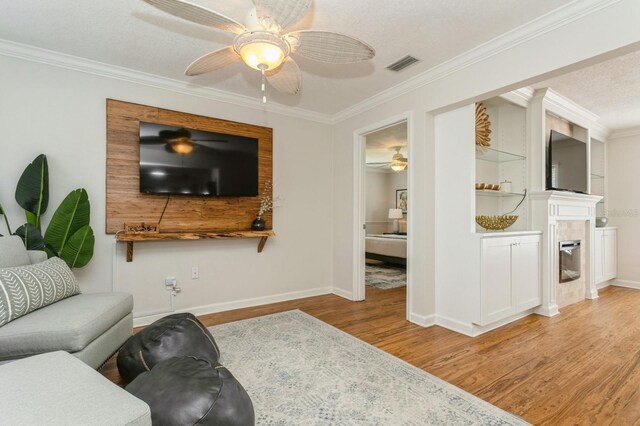 1304 63rd St NW, Bradenton, FL 34209 - living area with a ceiling fan, light wood-style floors, crown molding, and a fireplace