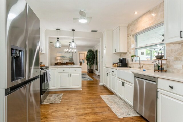 1304 63rd St NW, Bradenton, FL 34209 - kitchen featuring stainless steel appliances, white cabinetry, light wood-type flooring, and decorative backsplash