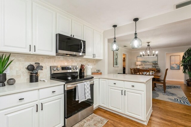 1304 63rd St NW, Bradenton, FL 34209 - kitchen with appliances with stainless steel finishes, a peninsula, backsplash, white cabinetry, and light countertops