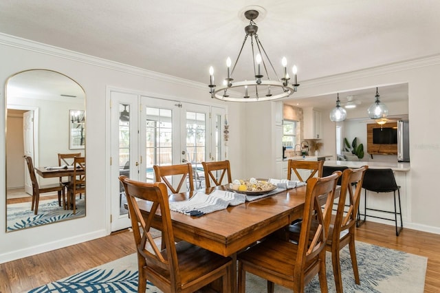 1304 63rd St NW, Bradenton, FL 34209 - dining space featuring crown molding, french doors, light wood finished floors, a chandelier, and arched walkways