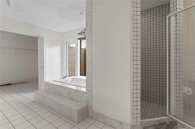 9311 136th Way, Seminole, FL 33776 - full bathroom featuring a shower stall, a garden tub, a textured ceiling, tile patterned flooring, and a spacious closet