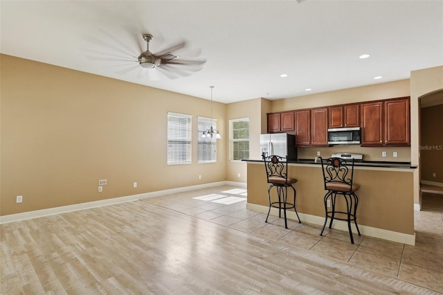 221 Sunset Crest Ct, Apollo Beach, FL 33572 - kitchen with stainless steel microwave, fridge with ice dispenser, dark countertops, a kitchen bar, and recessed lighting