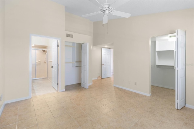 2231 Utopian Dr E Unit 307, Clearwater, FL 33763 - unfurnished bedroom featuring a towering ceiling, a spacious closet, ensuite bathroom, light tile patterned flooring, and ceiling fan