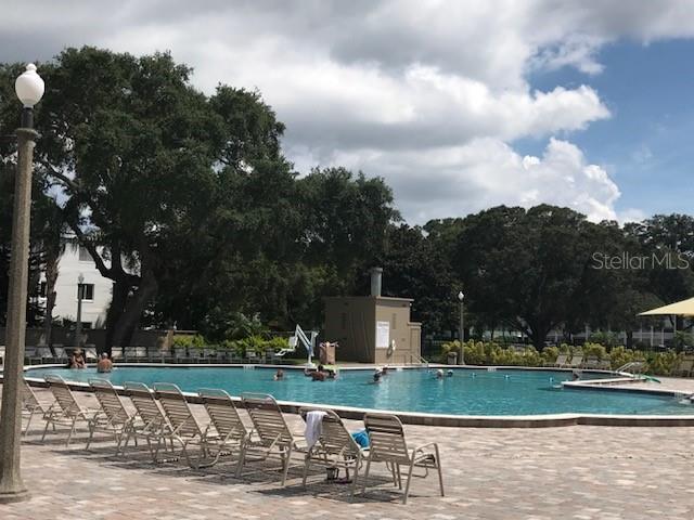 2231 Utopian Dr E Unit 307, Clearwater, FL 33763 - community pool featuring a patio and view of scattered trees
