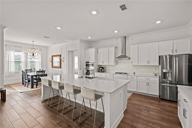 22034 Storybook Cabin Way, Land O Lakes, FL 34637 - kitchen featuring stainless steel appliances, wall chimney exhaust hood, ornamental molding, white cabinetry, and backsplash