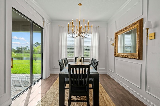 22034 Storybook Cabin Way, Land O Lakes, FL 34637 - dining area with a chandelier, a water view, crown molding, a decorative wall, and wood finished floors