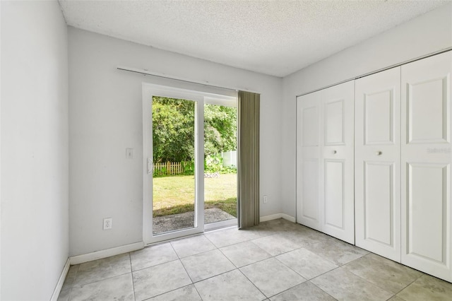 12315 Hidden Brook Dr, Tampa, FL 33624 - unfurnished bedroom featuring access to exterior, a textured ceiling, light tile patterned floors, and a closet