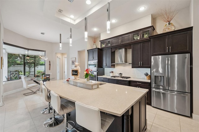 1042 Tuscany Dr, Trinity, FL 34655 - kitchen with appliances with stainless steel finishes, wall chimney exhaust hood, light tile patterned floors, an island with sink, and dark brown cabinetry