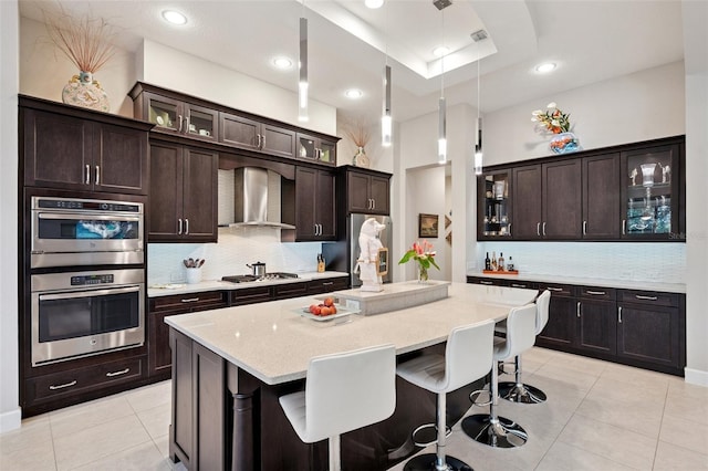 1042 Tuscany Dr, Trinity, FL 34655 - kitchen featuring wall chimney range hood, light tile patterned flooring, backsplash, a kitchen breakfast bar, and recessed lighting