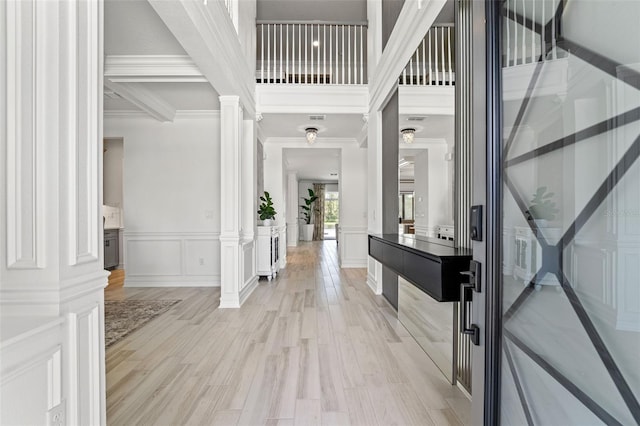 7819 Notched Pine Bnd, Wesley Chapel, FL 33545 - entrance foyer featuring ornate columns, crown molding, light wood-type flooring, a decorative wall, and a wainscoted wall