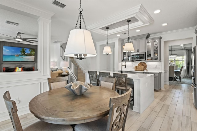 7819 Notched Pine Bnd, Wesley Chapel, FL 33545 - dining space featuring stairway, ornamental molding, a tray ceiling, a chandelier, and a ceiling fan