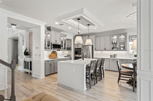 7819 Notched Pine Bnd, Wesley Chapel, FL 33545 - kitchen featuring gray cabinets, appliances with stainless steel finishes, a breakfast bar area, decorative backsplash, and light countertops