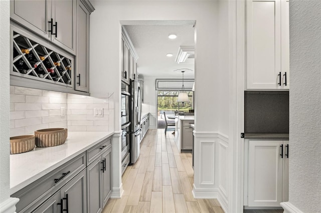 7819 Notched Pine Bnd, Wesley Chapel, FL 33545 - kitchen with gray cabinetry, tasteful backsplash, recessed lighting, light wood-type flooring, and light stone countertops