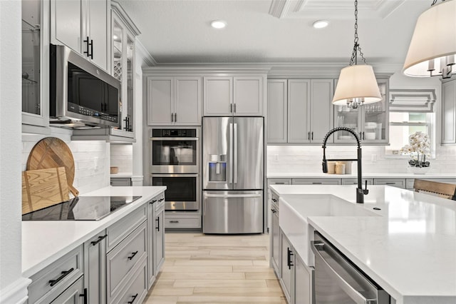 7819 Notched Pine Bnd, Wesley Chapel, FL 33545 - kitchen featuring stainless steel appliances, gray cabinets, crown molding, backsplash, and light wood-type flooring