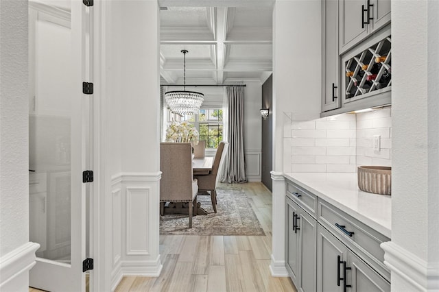 7819 Notched Pine Bnd, Wesley Chapel, FL 33545 - kitchen featuring gray cabinetry, crown molding, light wood finished floors, coffered ceiling, and light countertops