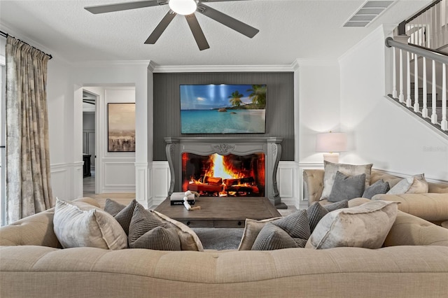 7819 Notched Pine Bnd, Wesley Chapel, FL 33545 - living room with ceiling fan, stairway, a lit fireplace, crown molding, and a decorative wall