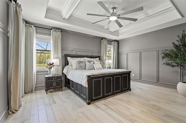 7819 Notched Pine Bnd, Wesley Chapel, FL 33545 - bedroom with a decorative wall, crown molding, a raised ceiling, light wood finished floors, and a ceiling fan