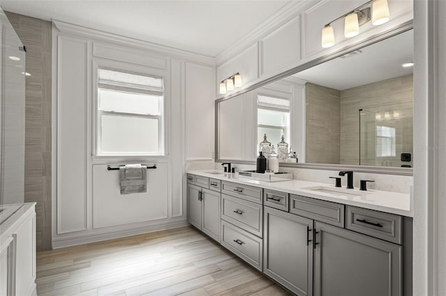 7819 Notched Pine Bnd, Wesley Chapel, FL 33545 - full bath featuring double vanity, a decorative wall, a tile shower, ornamental molding, and wood finished floors