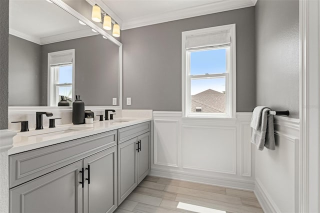 7819 Notched Pine Bnd, Wesley Chapel, FL 33545 - bathroom with double vanity, crown molding, a decorative wall, a wainscoted wall, and wood finished floors