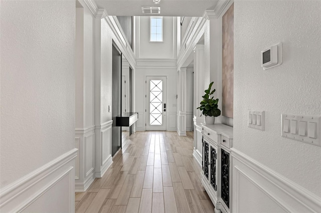 7819 Notched Pine Bnd, Wesley Chapel, FL 33545 - foyer entrance with a textured wall, crown molding, and light wood-style floors