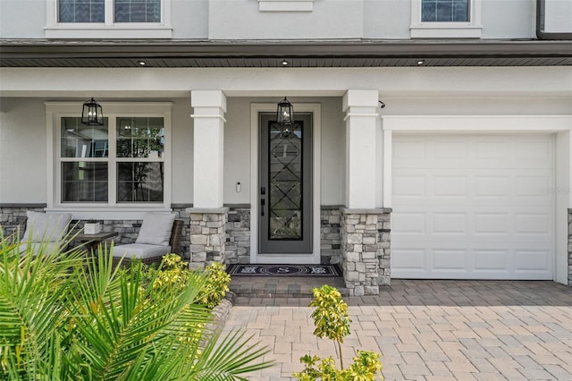 7819 Notched Pine Bnd, Wesley Chapel, FL 33545 - view of exterior entry featuring a porch, stucco siding, stone siding, and a garage