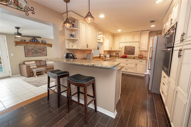 1132 Gershwin Dr, Largo, FL 33771 - kitchen featuring freestanding refrigerator, a peninsula, light stone countertops, dark wood-style floors, and pendant lighting