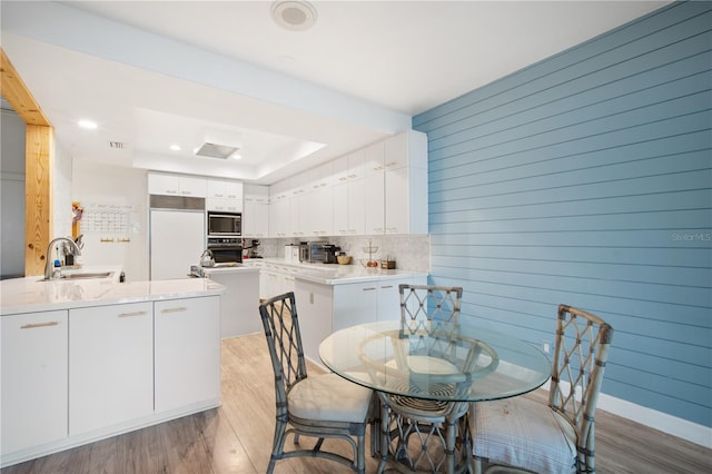 4719 61st Avenue Terrace W Unit 4719, Bradenton, FL 34210 - dining space featuring light wood-style floors, a tray ceiling, and wood walls