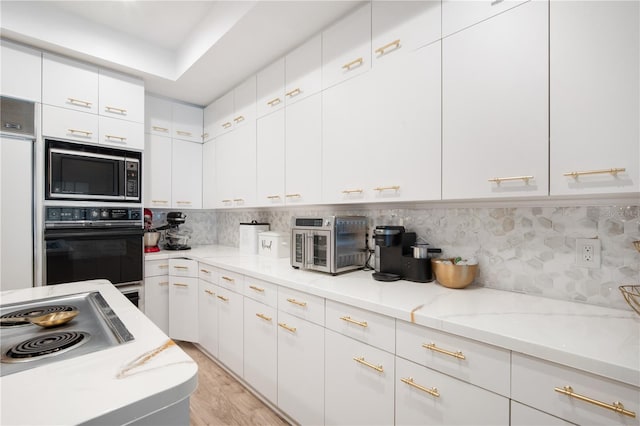 4719 61st Avenue Terrace W Unit 4719, Bradenton, FL 34210 - kitchen with built in microwave, white cabinets, tasteful backsplash, stovetop, and light stone countertops