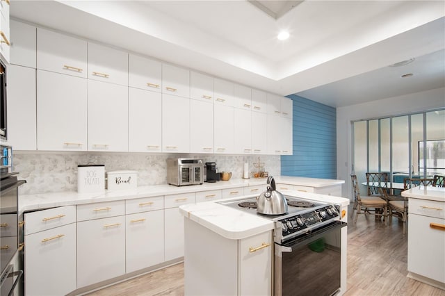 4719 61st Avenue Terrace W Unit 4719, Bradenton, FL 34210 - kitchen with black range with electric stovetop, light wood-style floors, backsplash, white cabinetry, and recessed lighting