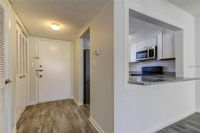 4901 Onyx Ln Unit 204, New Port Richey, FL 34652 - kitchen featuring stainless steel appliances, wood finished floors, backsplash, white cabinetry, and a textured ceiling