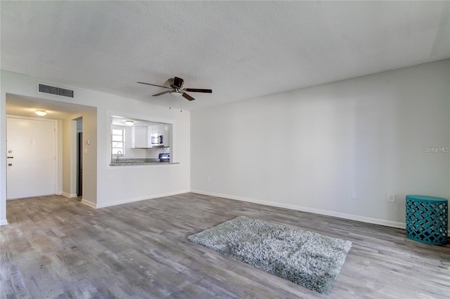 4901 Onyx Ln Unit 204, New Port Richey, FL 34652 - unfurnished living room featuring a ceiling fan, wood finished floors, and a textured ceiling