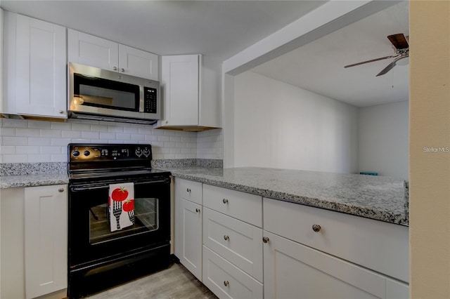 4901 Onyx Ln Unit 204, New Port Richey, FL 34652 - kitchen with stainless steel microwave, black electric range, backsplash, and white cabinetry