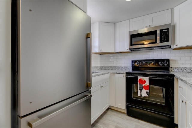 4901 Onyx Ln Unit 204, New Port Richey, FL 34652 - kitchen featuring stainless steel appliances, white cabinetry, backsplash, light wood finished floors, and light stone countertops