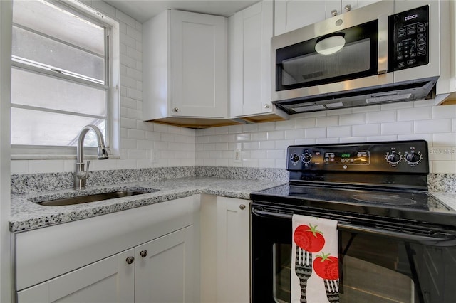 4901 Onyx Ln Unit 204, New Port Richey, FL 34652 - kitchen featuring stainless steel microwave, electric range, white cabinets, and decorative backsplash