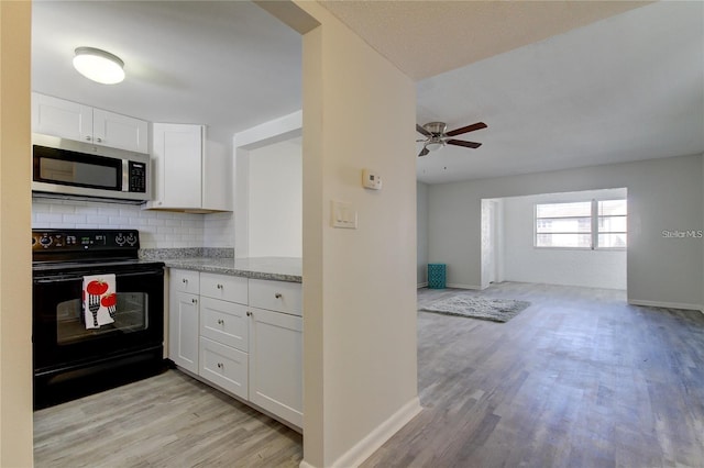 4901 Onyx Ln Unit 204, New Port Richey, FL 34652 - kitchen with stainless steel microwave, black / electric stove, light wood-style floors, decorative backsplash, and white cabinetry