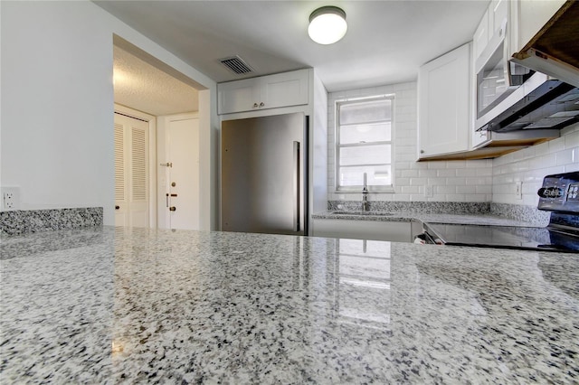4901 Onyx Ln Unit 204, New Port Richey, FL 34652 - kitchen featuring stainless steel appliances, white cabinetry, light stone countertops, and backsplash
