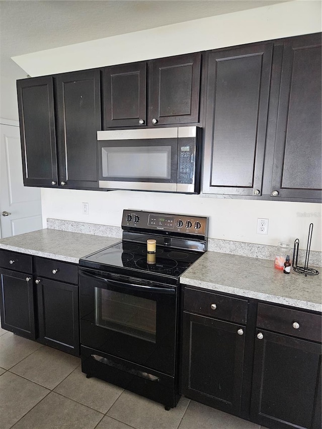 10124 Mangrove Well Rd, Ruskin, FL 33573 - kitchen with electric range, stainless steel microwave, light tile patterned flooring, and light countertops