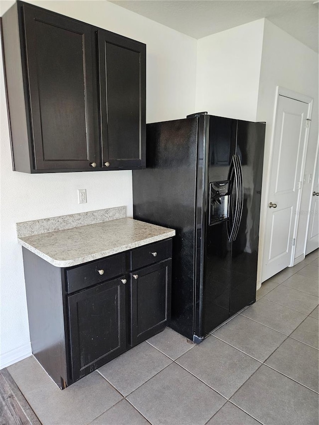 10124 Mangrove Well Rd, Ruskin, FL 33573 - kitchen featuring black fridge with ice dispenser, dark cabinetry, light countertops, and light tile patterned floors