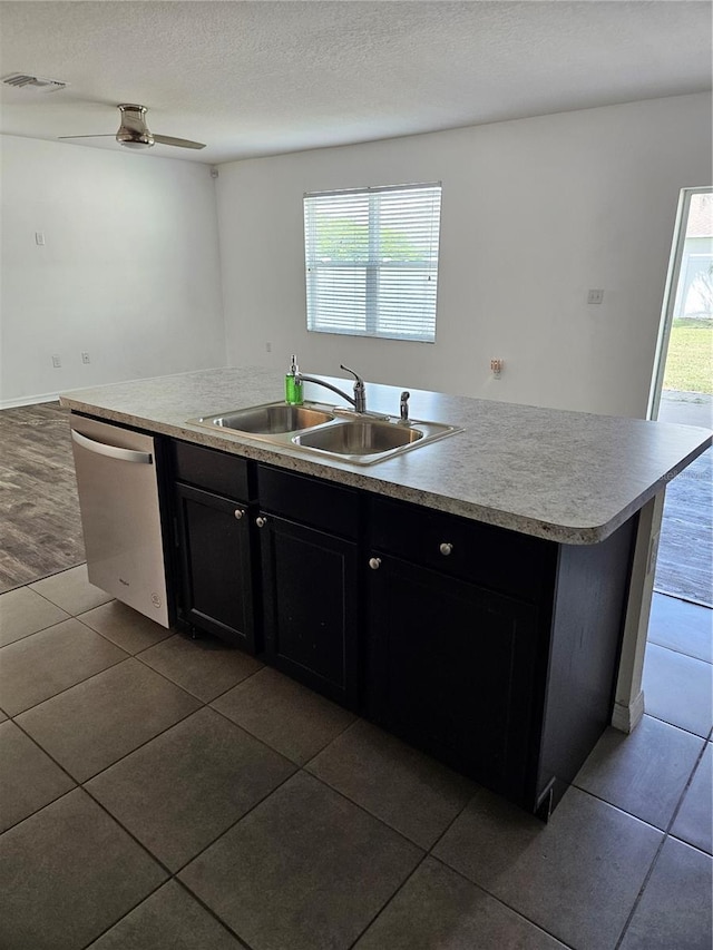 10124 Mangrove Well Rd, Ruskin, FL 33573 - kitchen with stainless steel dishwasher, dark tile patterned floors, dark cabinetry, light countertops, and a center island with sink