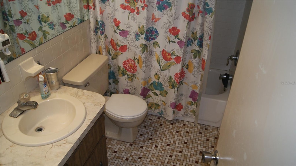 7705 Embassy Blvd, Port Richey, FL 34668 - full bathroom with vanity, tile patterned flooring, shower / bath combo with shower curtain, and tile walls