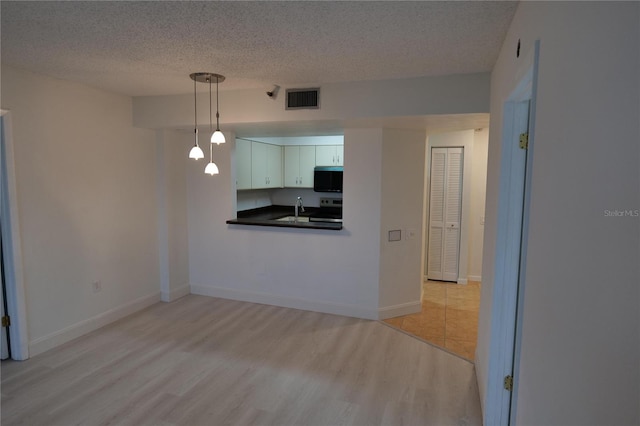 2333 Feather Sound Dr Unit A607, Clearwater, FL 33762 - kitchen featuring stainless steel electric range, dark countertops, a textured ceiling, light wood finished floors, and white cabinetry