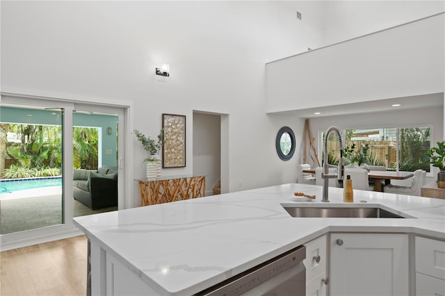 221 42nd Ave, St Pete Beach, FL 33706 - kitchen featuring dishwasher, light stone countertops, white cabinetry, healthy amount of natural light, and a towering ceiling