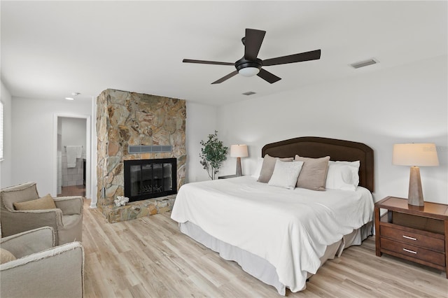 221 42nd Ave, St Pete Beach, FL 33706 - bedroom with light wood-type flooring, a stone fireplace, and a ceiling fan