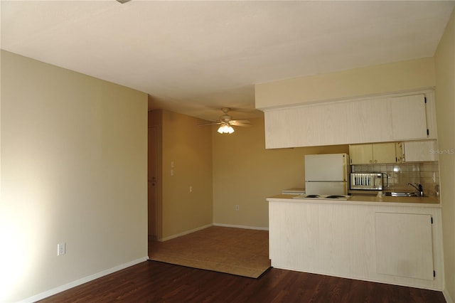 4329 Tahitian Gardens Cir Unit B, Holiday, FL 34691 - kitchen with freestanding refrigerator, dark wood-style floors, a ceiling fan, a peninsula, and decorative backsplash