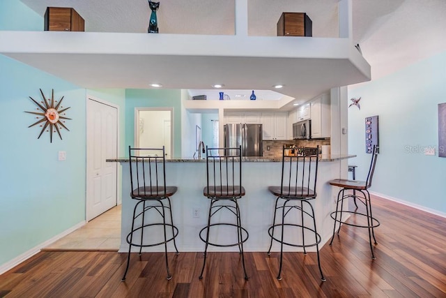 1140 S Pointe Alexis Dr, Tarpon Springs, FL 34689 - kitchen featuring appliances with stainless steel finishes, light wood finished floors, white cabinets, a breakfast bar, and recessed lighting